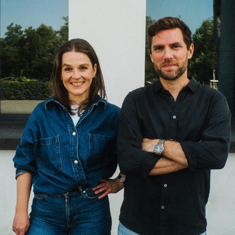 Andrea und Frank Zwei Personen stehen zusammen und lächeln. Andrea Engel in Jeans und Hemd, Frank Röhrig in dunklem Hemd.